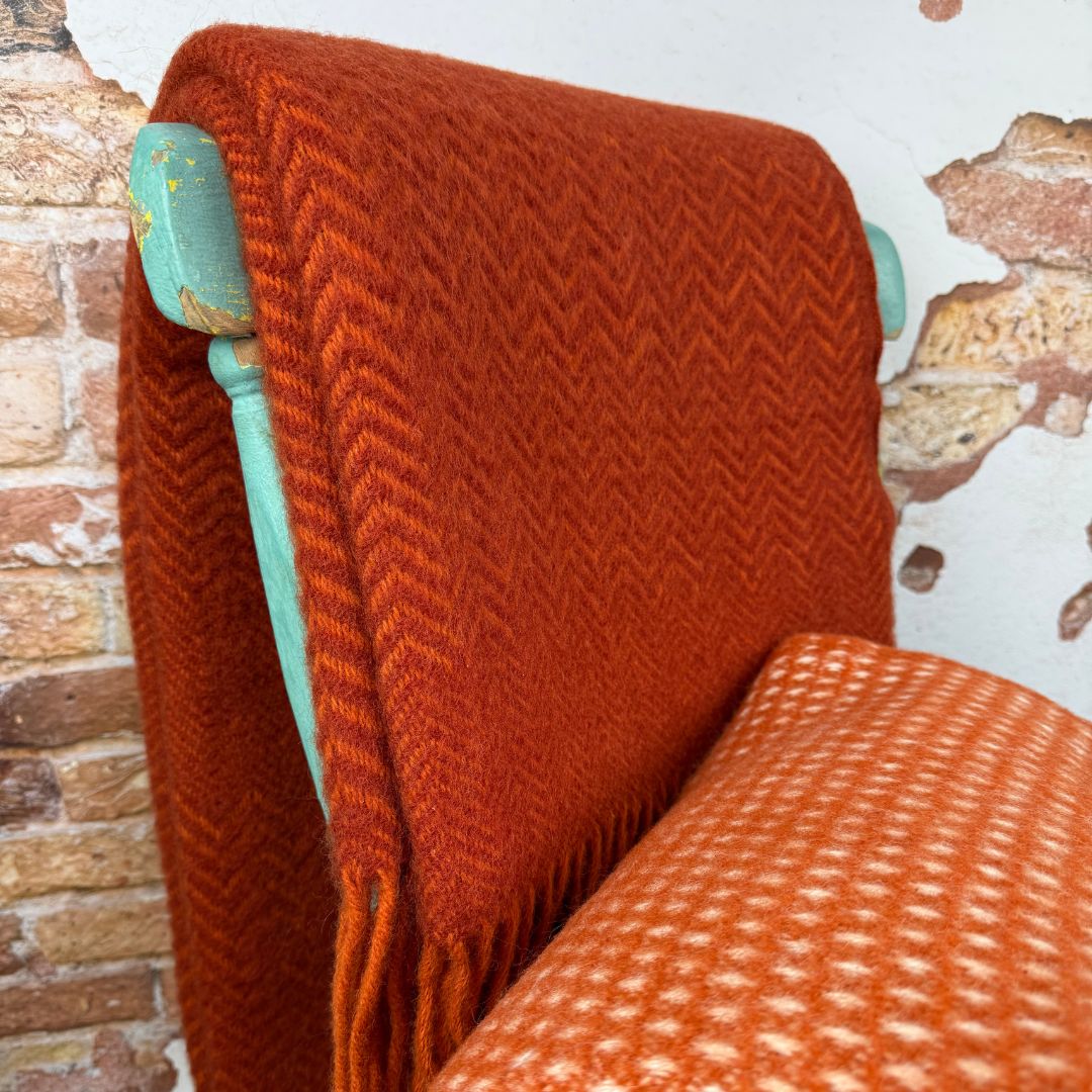 Orange wool throws on a chair with a wall background