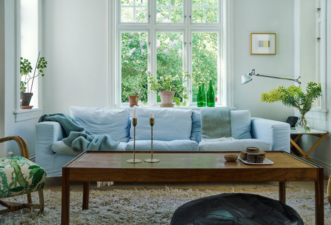 Blue wool throws on a white sofa in a room with a table and chair and lamp