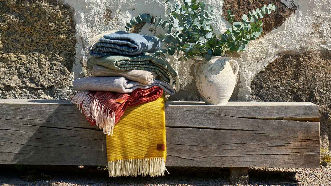 Hugo recycled merino wool throws folded on a bench
