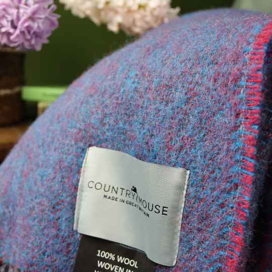 Wool Throw with 'Countrymouse' label and flowers in the background