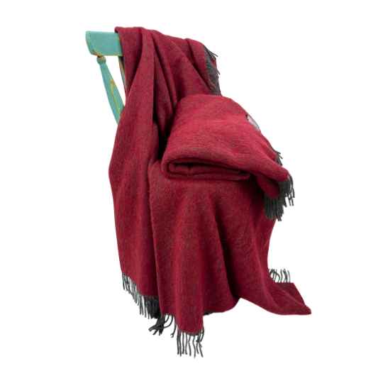 Cherry Red blanket with black fringe draped over a chair on a white background