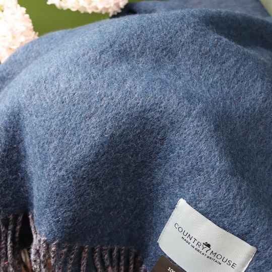 Close-up of a blue blanket with a 'Country Mouse' label on a floral background