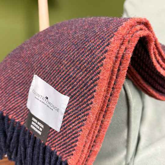 burnt terracotta Woven blanket with a visible brand label on a neutral background