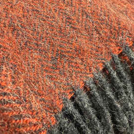 close up of orangernt orange wool throw showing grey tassles