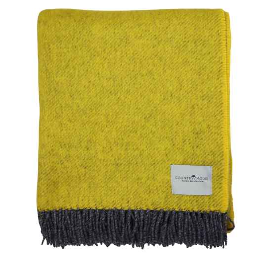 Yellow throw blanket with a gray fringe and a brand label on a white background