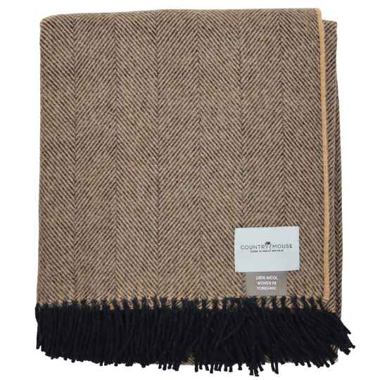 Woven blanket with herringbone pattern and black fringe, featuring a label on a white background.
