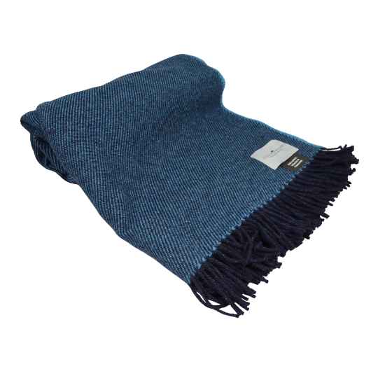 deep teal wool throw rolled up against a white background