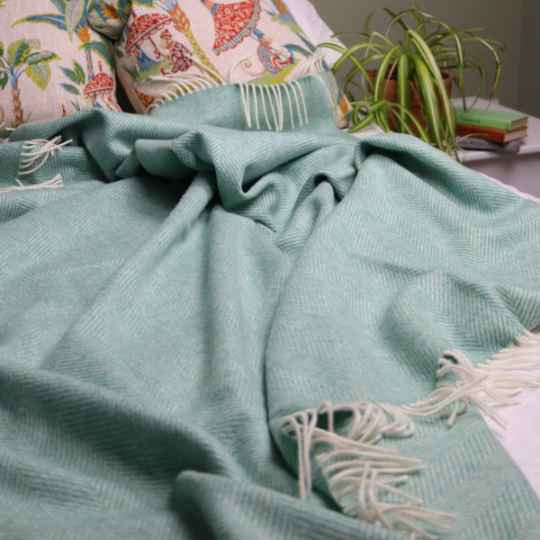 eucalyptus herringbone merino wool blanket on a bed