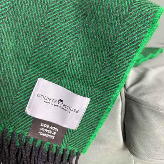 Green  herringbone patterned blanket with a 'Country Mouse' label on a neutral background