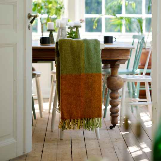 gotland orange check wool throw on a chair with a table and chairs by a window
