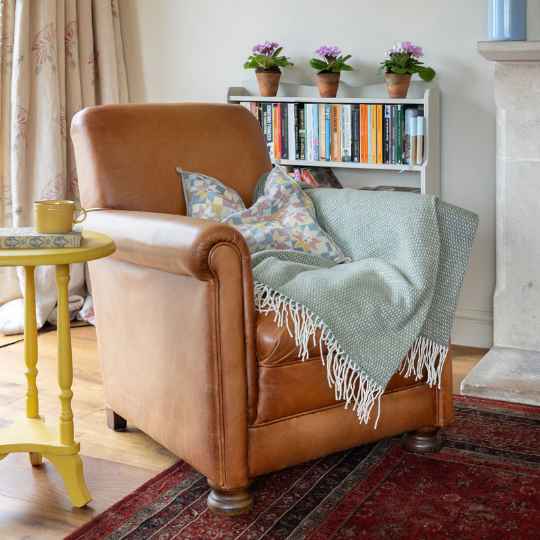 Hugo dusty green merino wool throw on a armchair
