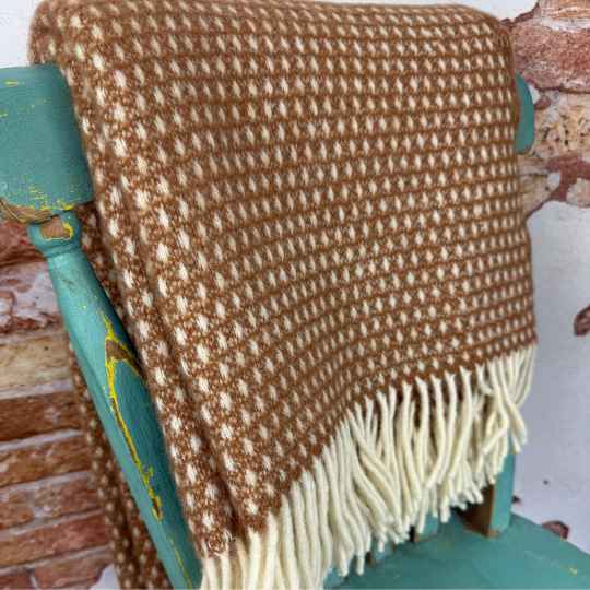 Brown and white patterned blanket draped over a teal chair.