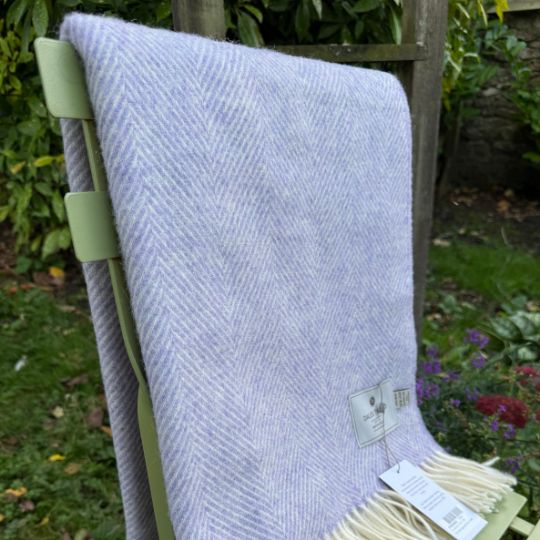 parma violet herringbone wool throw on a chiar in a garden