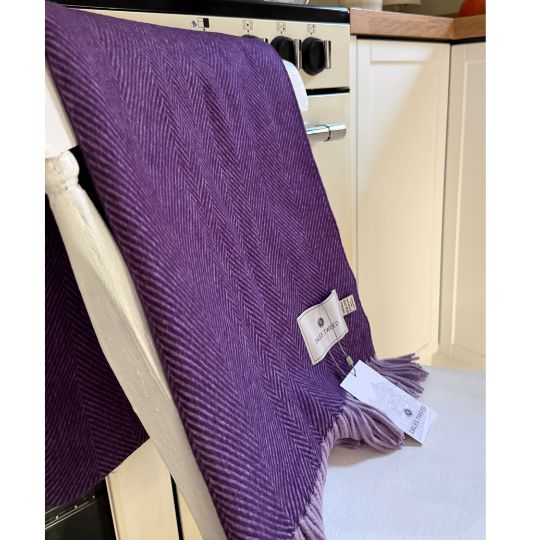 purle herringbone wool throw on a white chair against a cream cooker in a kitchen