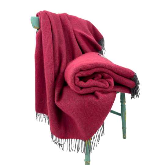 raspberry wool throw on a chair agaisnst a white background