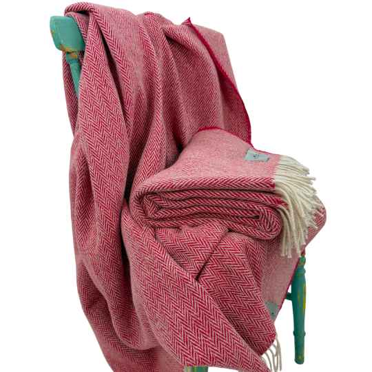 Red woven wool  blanket draped over a turquoise chair on a white background