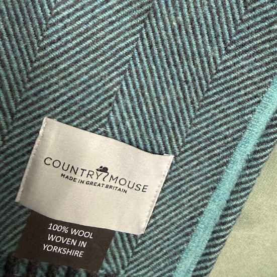blue wool throw with 'Country Mouse' label indicating 100% wool from Yorkshire