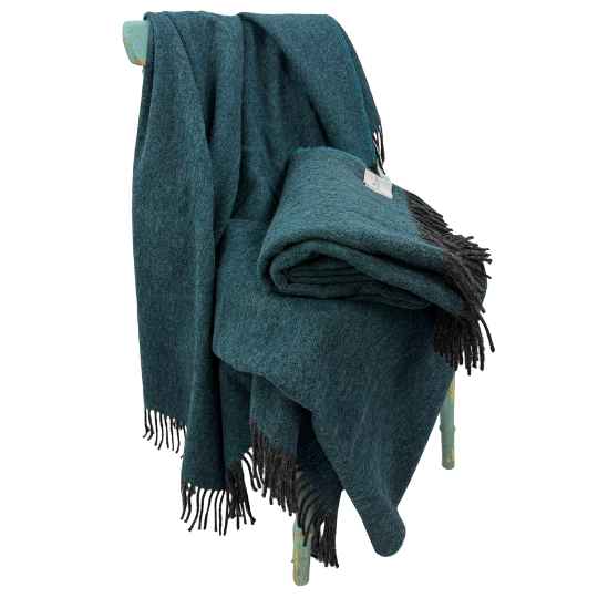 tealecycled herringbone wool throw on a chair against a white background