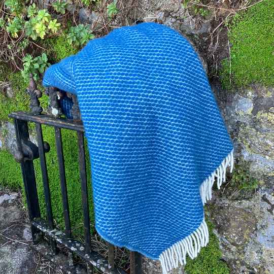 Velvet Petrol Blue Wool throw draped over a gate outdoors