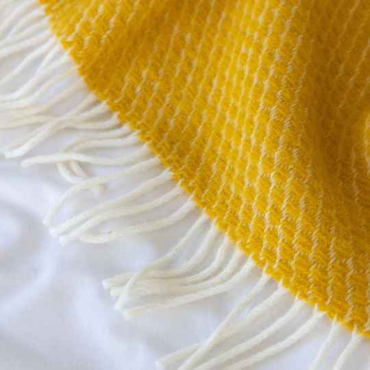 Velvet saffron wool throw showing a close up of the cream tassels