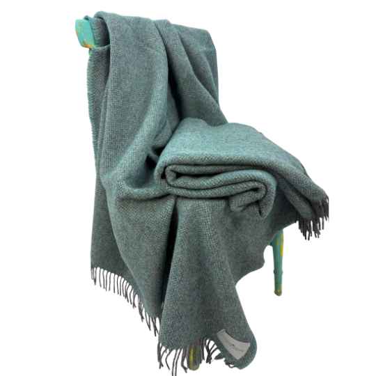 Folded winter teal blanket with fringes on a white background