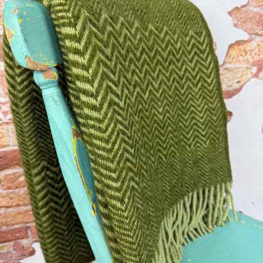 Green zig zag blanket draped over a teal chair.